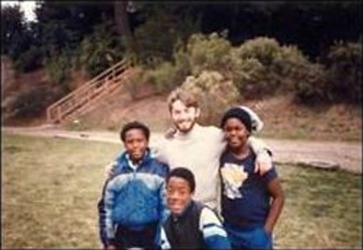 A staff member with three boys outdoors in the 1980s