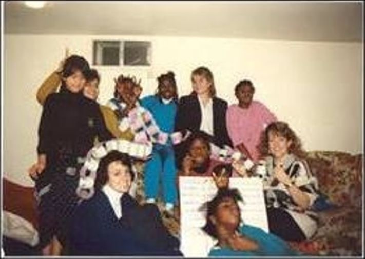 Children and adults indoors holding a long paper chain in the late 1980s