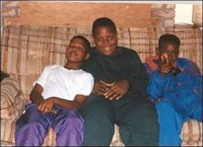 Three boys sitting together on a couch in the 1990s