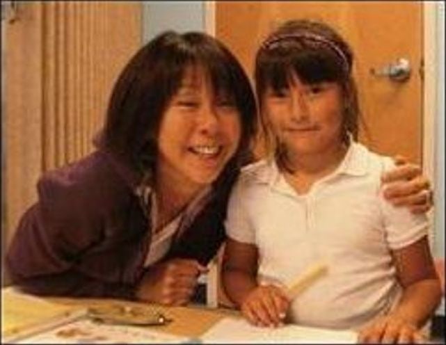 A mentor with her arm around a young girl at a desk