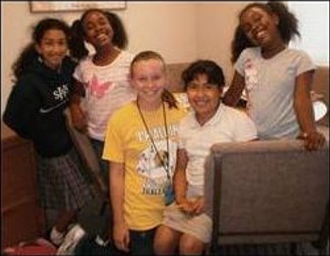 Five girls posing and smiling together indoors