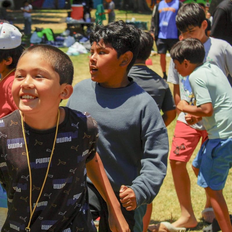 A smiling student outdoors with friends on the field