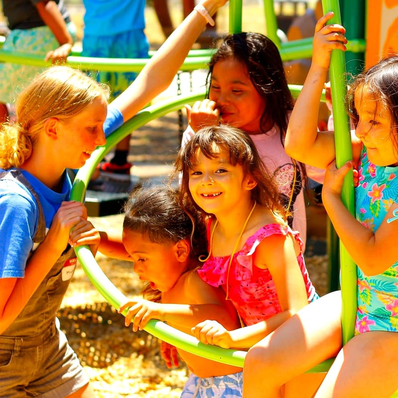 A group of children playing together on the playground climbing frame