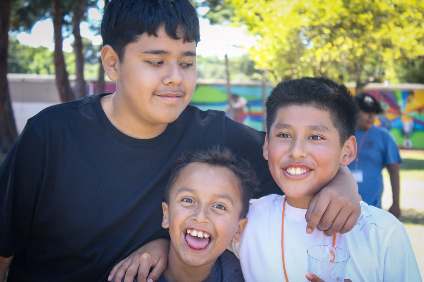 Two older Hope Horizon students and a younger child laughing together outdoors