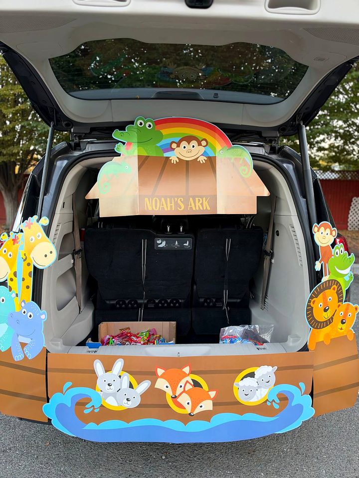 A trunk decorated as Noah's Ark with cutout giraffes, a lion, a rainbow and animals in the waves
