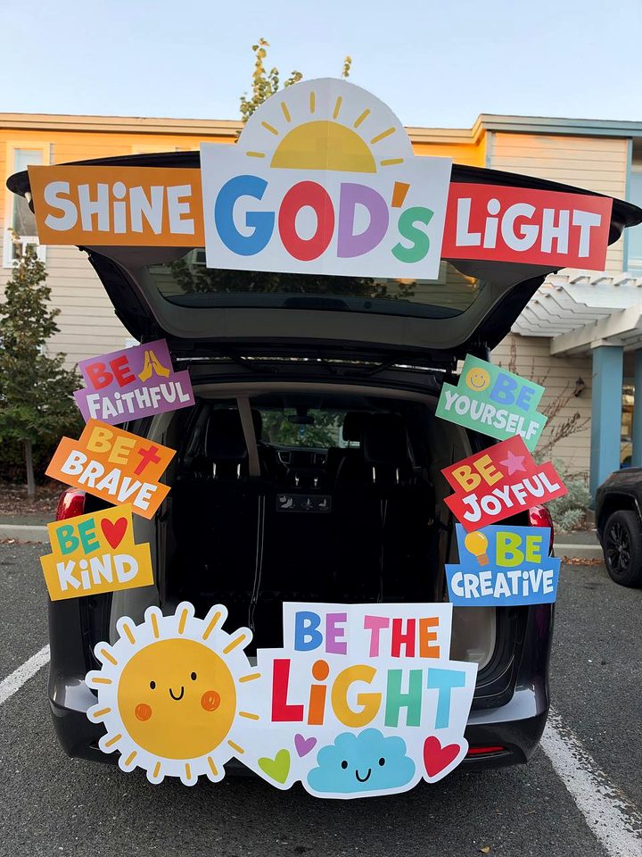 A trunk covered in colorful signs reading Shine God's Light, Be Kind, Be Brave, Be Joyful and Be the Light