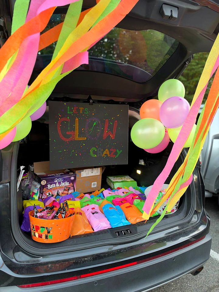 A trunk with neon streamers, balloons, a hand painted Let's Glow Crazy sign and bags of treats
