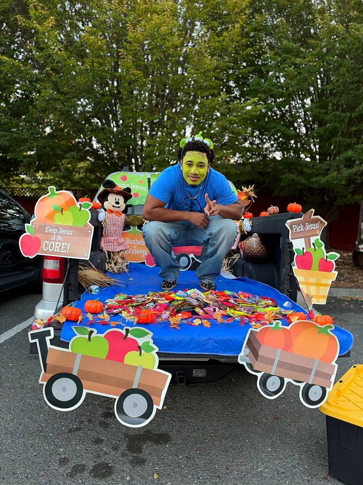 A pickup truck bed covered in candy between two cutout apple carts, with signs reading Keep Jesus at the Core and Pick Jesus