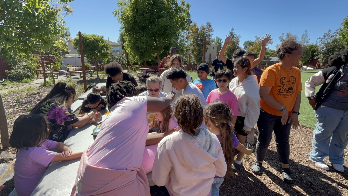 Scott Cunningham with a group of Hope Horizon students around a table outdoors.